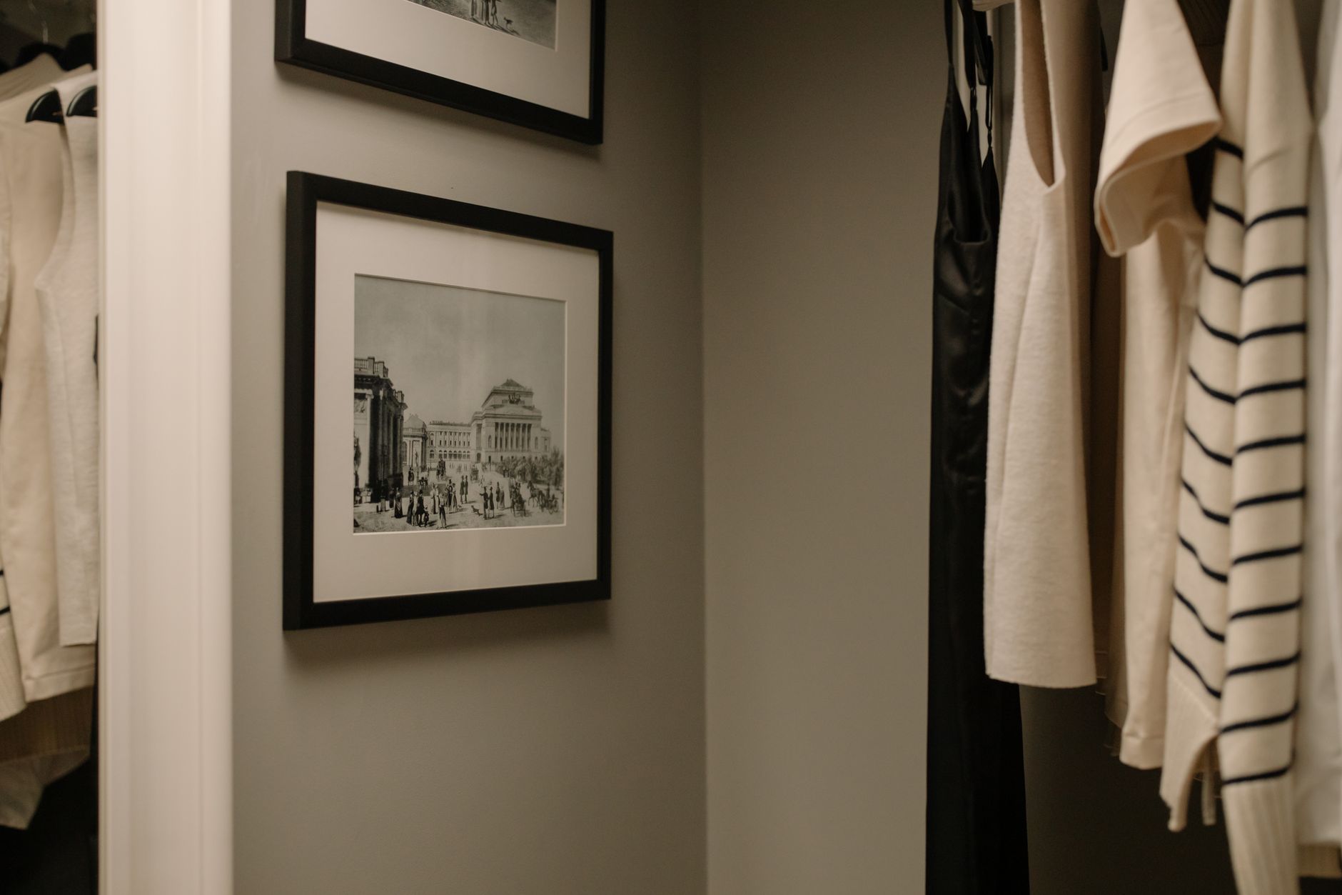 A well-organised closet with a few hanging clothes.