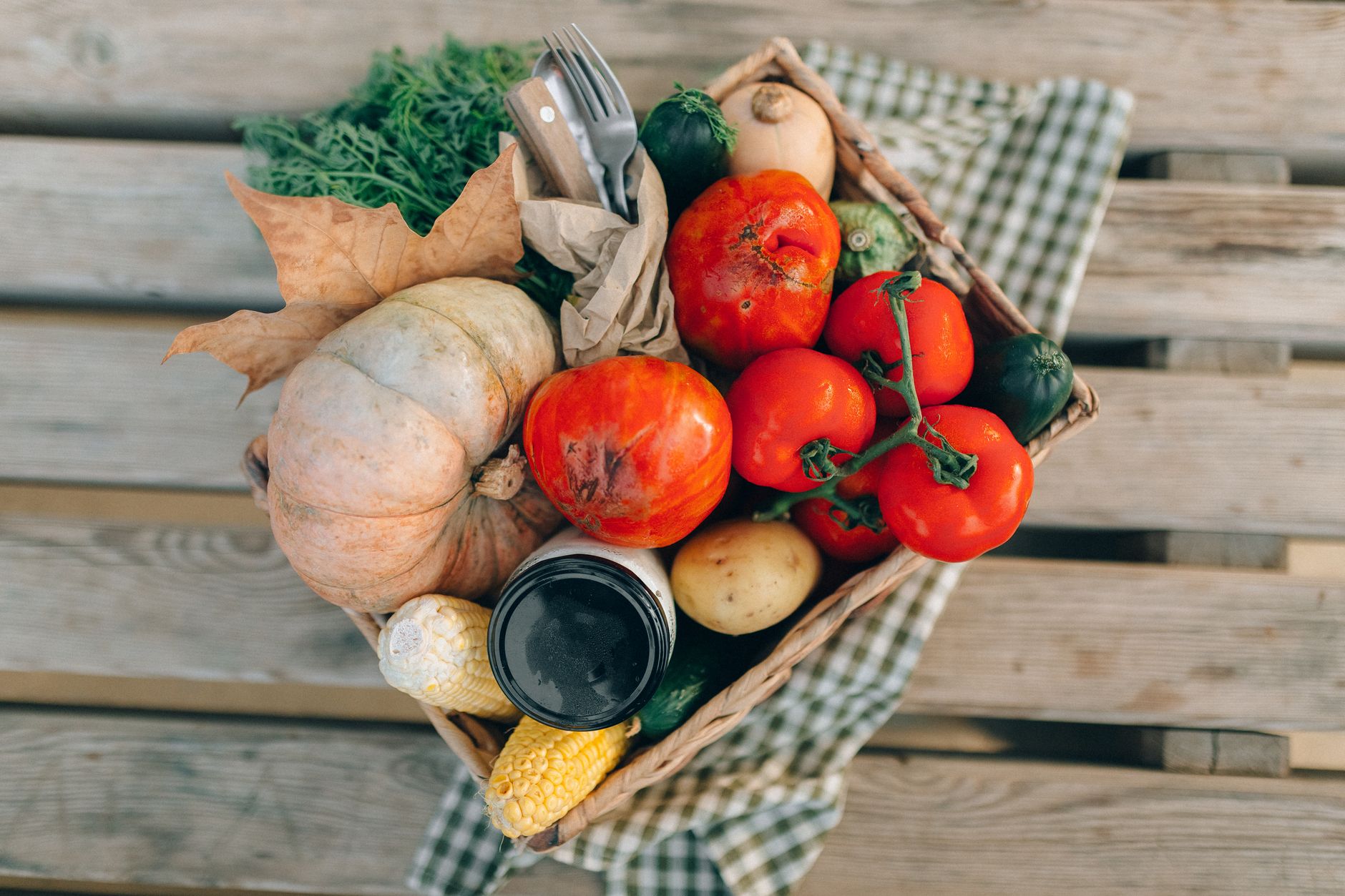 A basket of fresh seasonal vegetables on a wooden table.